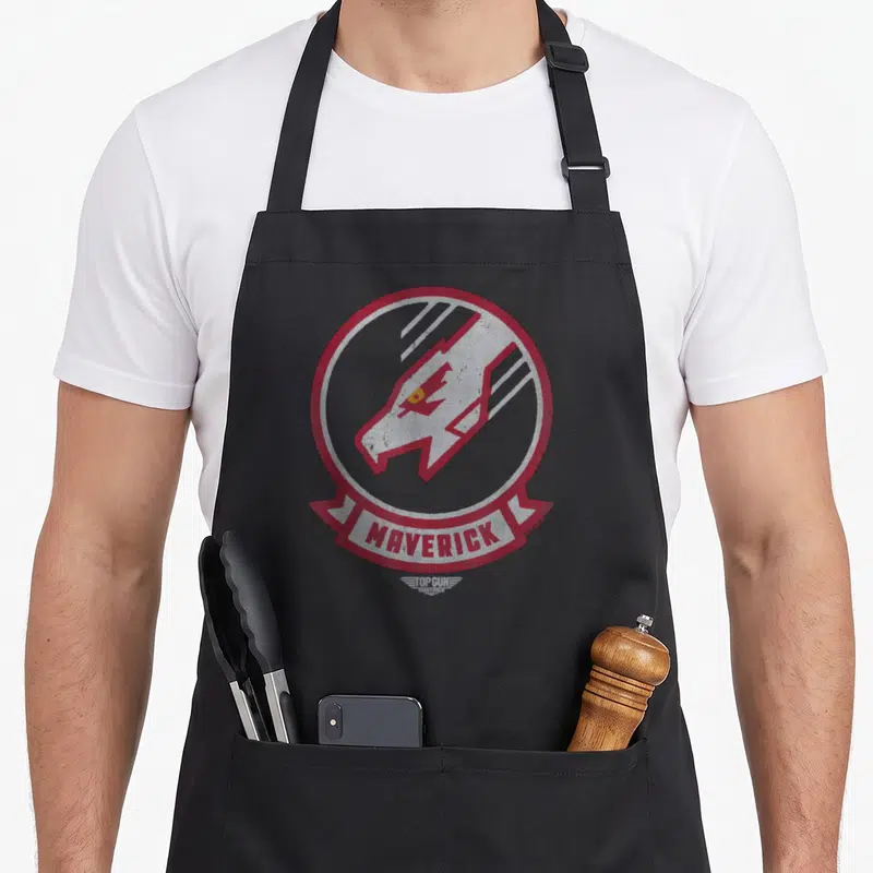 Tablier de cuisine noir avec un logo circulaire rouge et blanc représentant la tête d'un loup et le mot MAVERICK en bas.