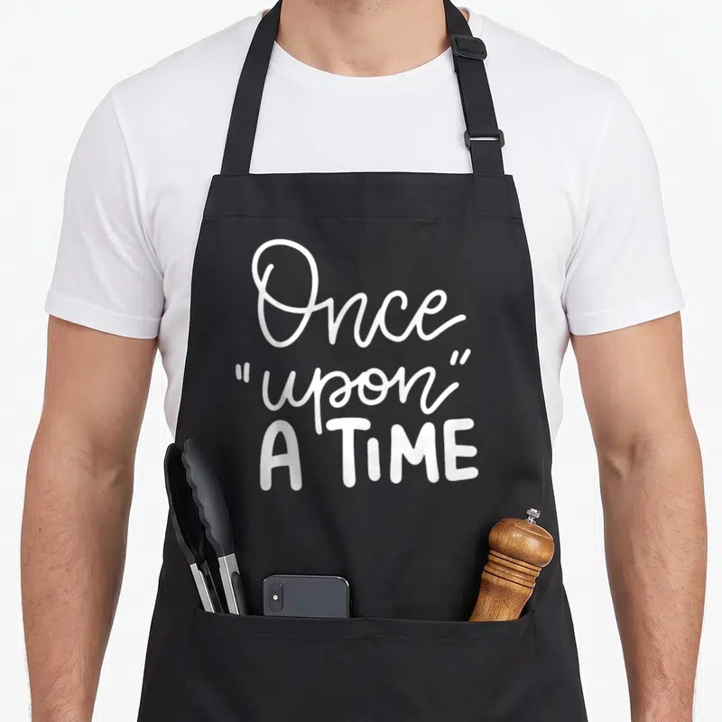 Tablier de cuisine noir avec le texte blanc Once upon a time en typographie manuscrite et capitales.