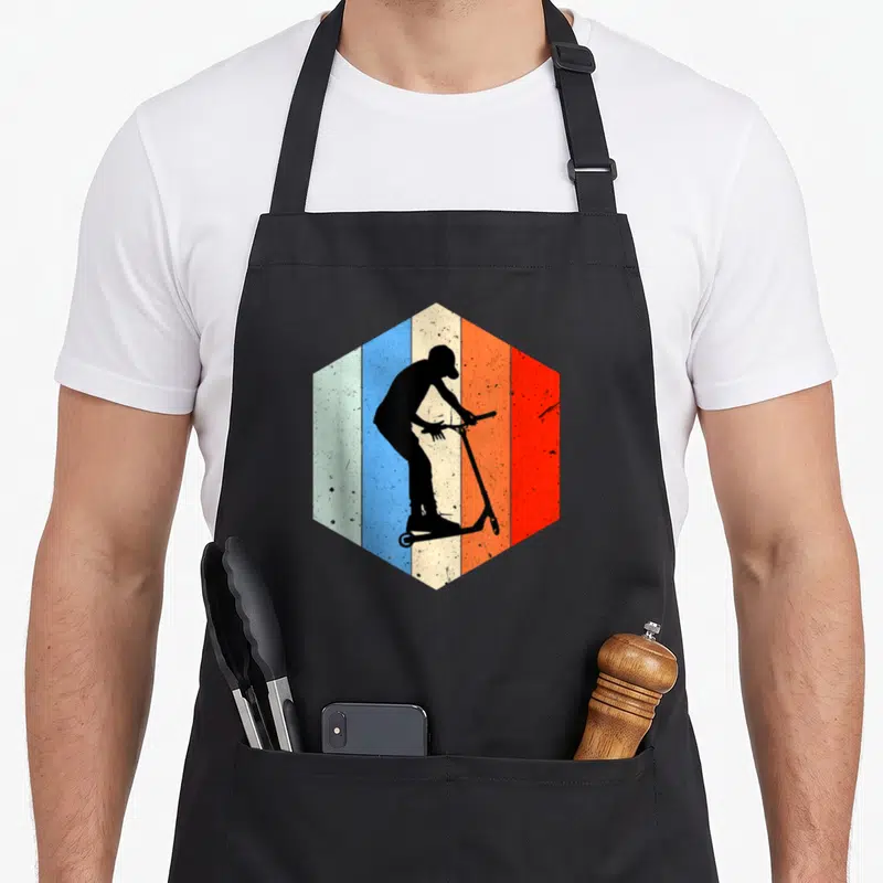 Tablier de cuisine noir avec une silhouette de trottinette freestyle sur fond hexagonal multicolore vintage.