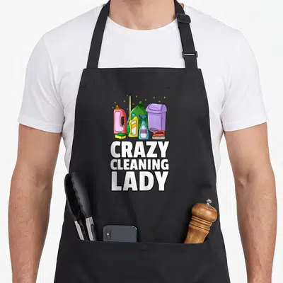 Tablier de cuisine noir avec illustration de produits de ménage et texte Crazy Cleaning Lady en grosses lettres blanches.