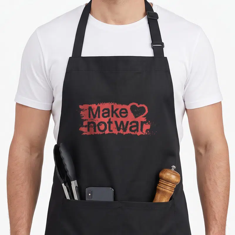 Tablier de cuisine noir avec inscription rouge Make Love Not War et cœur stylisé au centre du motif.
