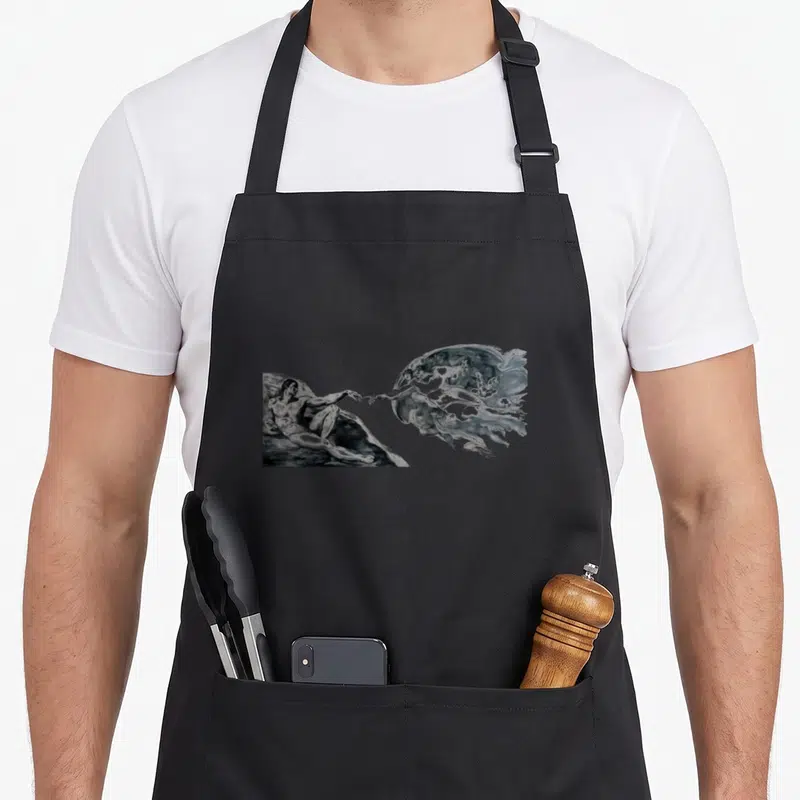 Tablier de cuisine noir avec reproduction monochrome de la Création d'Adam de Michel-Ange imprimée sur le devant.