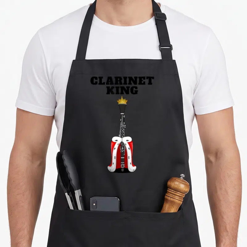 Tablier de cuisine noir avec une clarinette portant une couronne et une cape rouge.