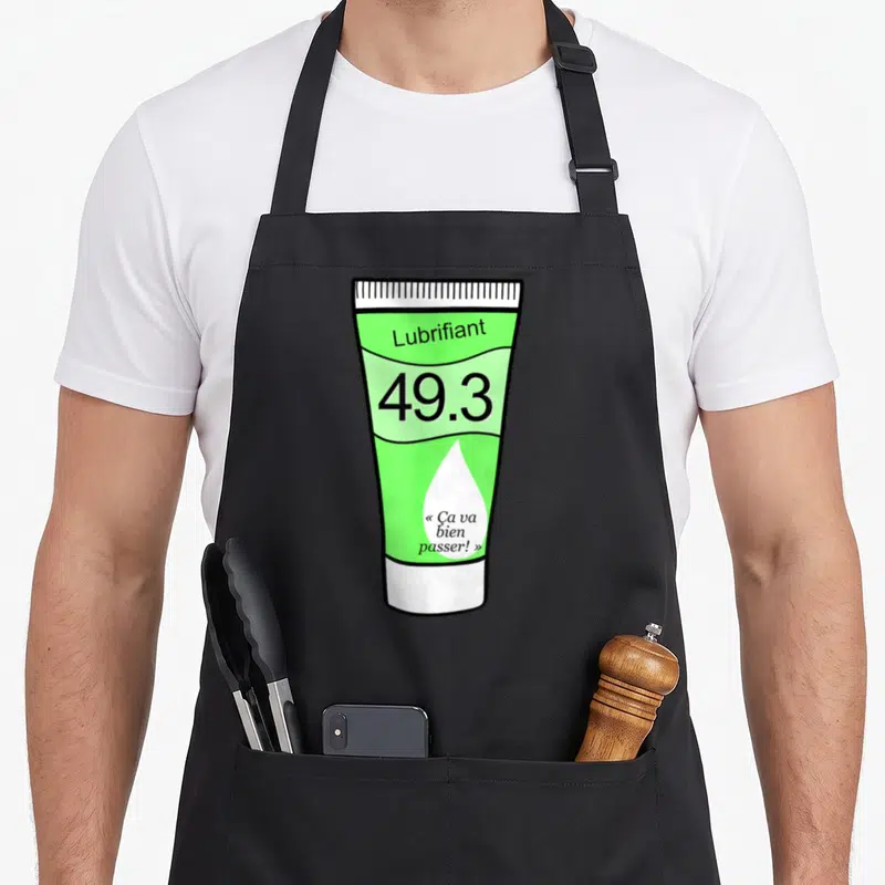 Tablier de cuisine noir avec illustration d'un tube vert lubrifiant portant la mention 49.3 ça va bien passer.