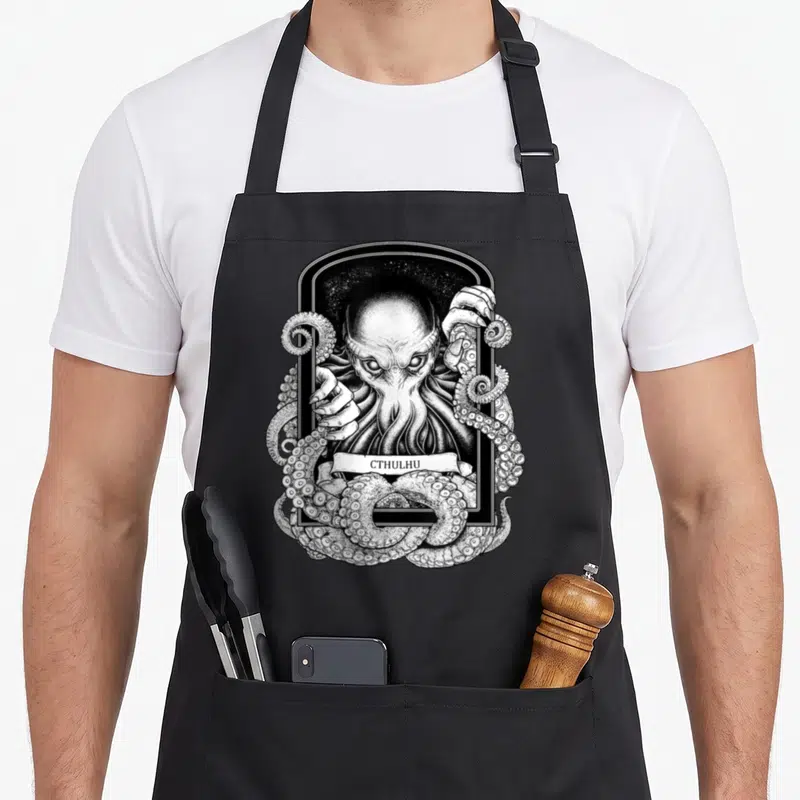 Tablier de cuisine noir avec illustration gravure de Cthulhu aux tentacules et bannière nommant le monstre.