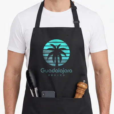 Tablier de cuisine noir avec un palmier turquoise et linscription Guadalajara Mexico en bas du motif circulaire.