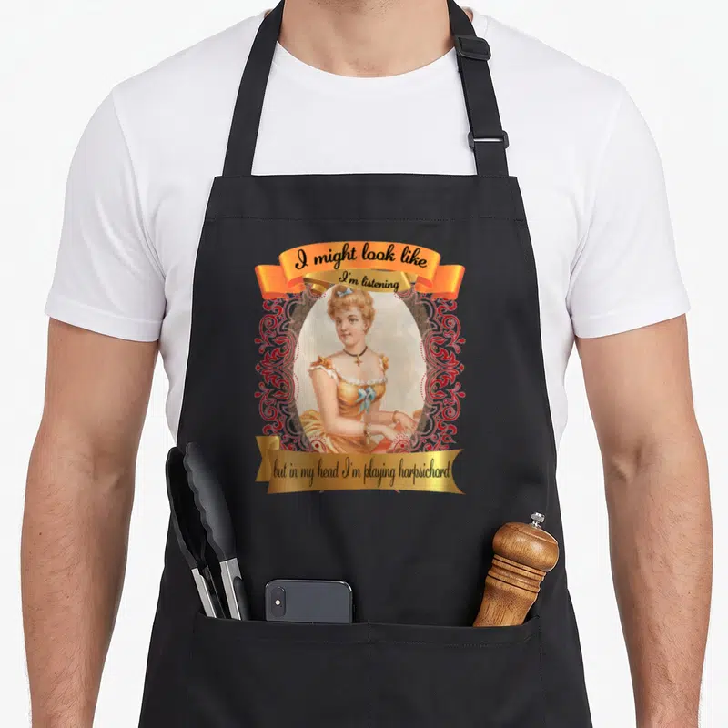 Tablier de cuisine noir avec illustration vintage d'une femme en robe jaune et bandes orange portant le texte I might look like but in my head I'm playing harpsichord.