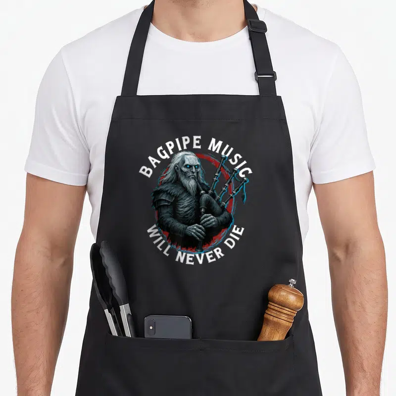 Tablier de cuisine noir avec illustration d'un cornemuseur barbu jouant du bagpipe sous le texte Bagpipe Music Will Never Die.