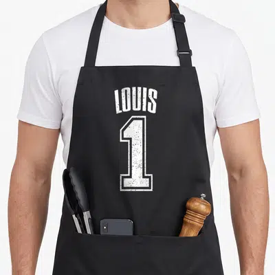 Tablier de cuisine noir avec le nom Louis et le chiffre 1 en blanc style maillot de sport vintage.