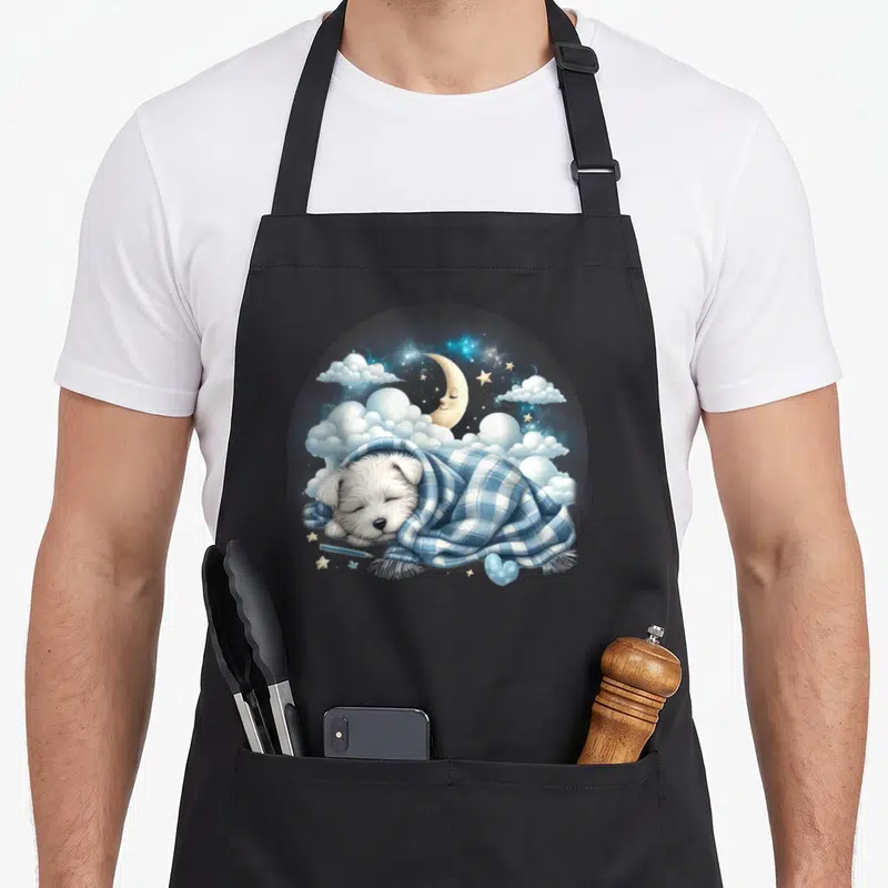 Tablier de cuisine noir avec Westie endormi sous couverture bleue, lune et étoiles en arrière-plan.