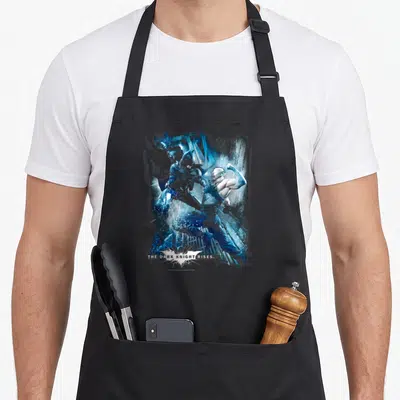 Tablier de cuisine noir avec illustration de combat entre Batman et Bane en bleu et le titre du film en bas.