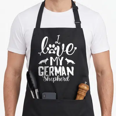 Tablier de cuisine noir avec deux silhouettes de chiens et une patte stylisée en blanc sur le devant.