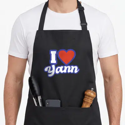 Tablier de cuisine noir avec inscription I cœur Yann en blanc et bleu vif au centre du torse.