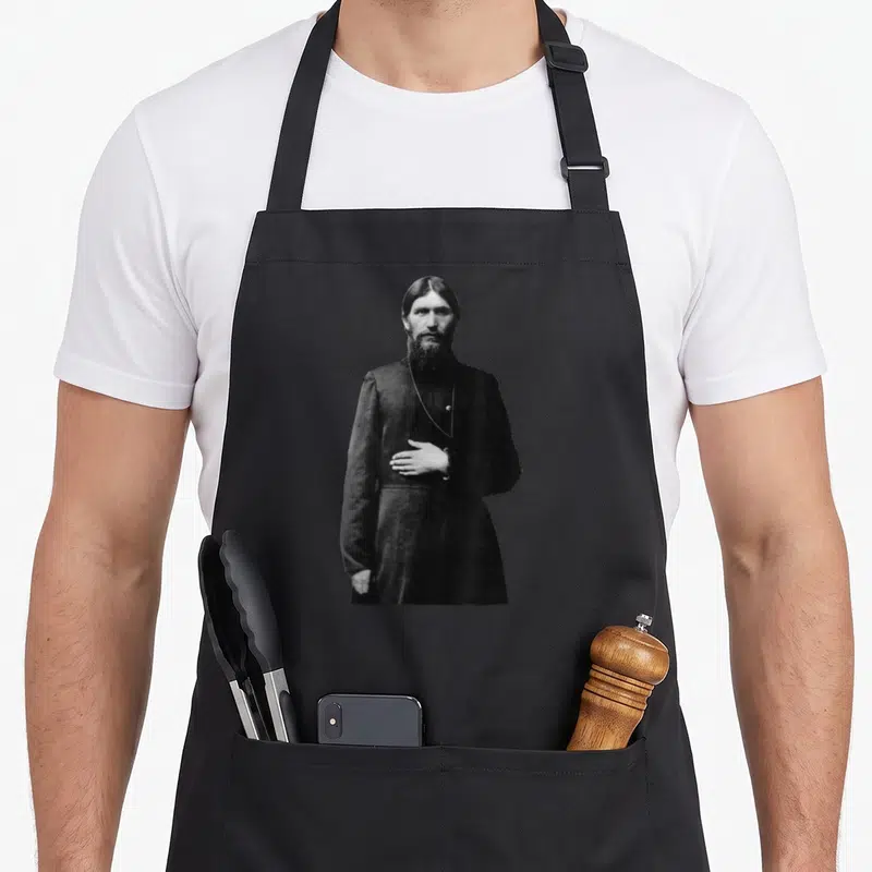 Tablier de cuisine noir avec portrait monochrome de Rasputin le moine fou, vêtu d'une longue robe sombre.
