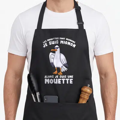 Tablier de cuisine noir avec une mouette aux lunettes noires et texte humoristique blanc sur fond uni.