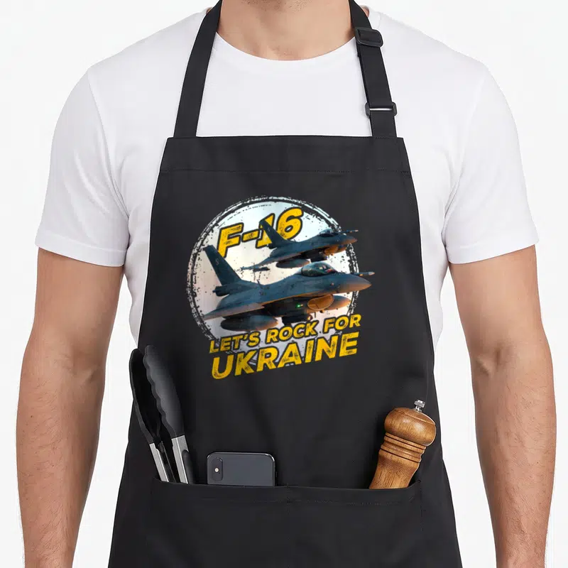 Tablier de cuisine noir avec illustration d'un avion F-16 et le texte Let's Rock for Ukraine en jaune.