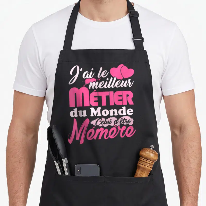 Tablier de cuisine noir avec inscription rose J'ai le meilleur métier du monde celui d'être Mémère et deux cœurs en haut à droite.