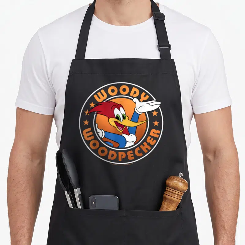 Tablier de cuisine noir avec le logo circulaire coloré de Woody Woodpecker en train de saluer.
