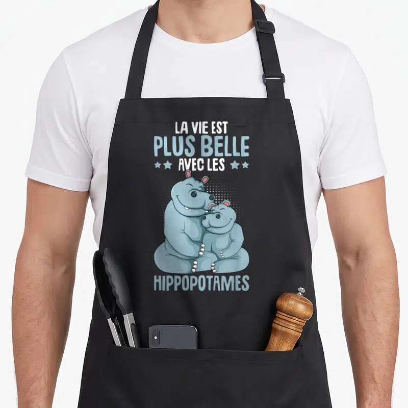 Tablier de cuisine noir avec illustration d'un grand et un petit hippopotame bleu s'enlaçant sous le texte La Vie Est Plus Belle Avec Les Hippopotames.