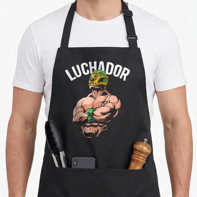 Tablier de cuisine noir avec illustration d'un Luchador masqué aux bras croisés et le texte LUCHADOR en blanc.
