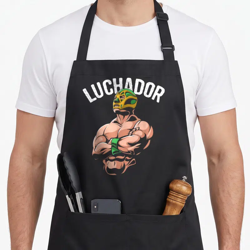 Tablier de cuisine noir avec illustration d'un Luchador masqué aux bras croisés et le texte LUCHADOR en blanc.