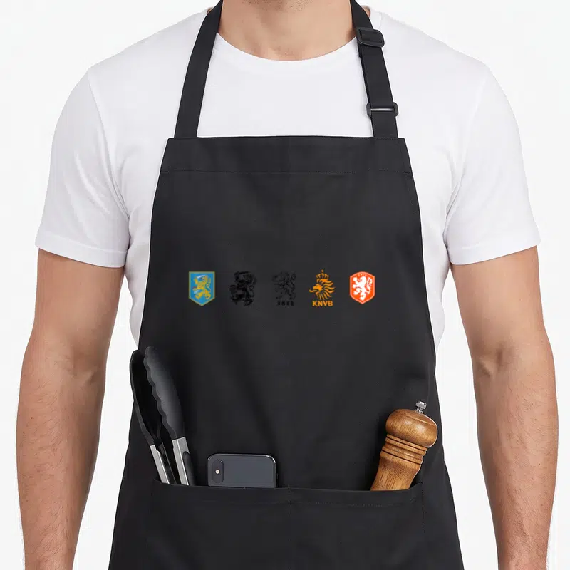 Tablier de cuisine noir avec cinq logos successifs de la KNVB représentant l'évolution du lion héraldique néerlandais.