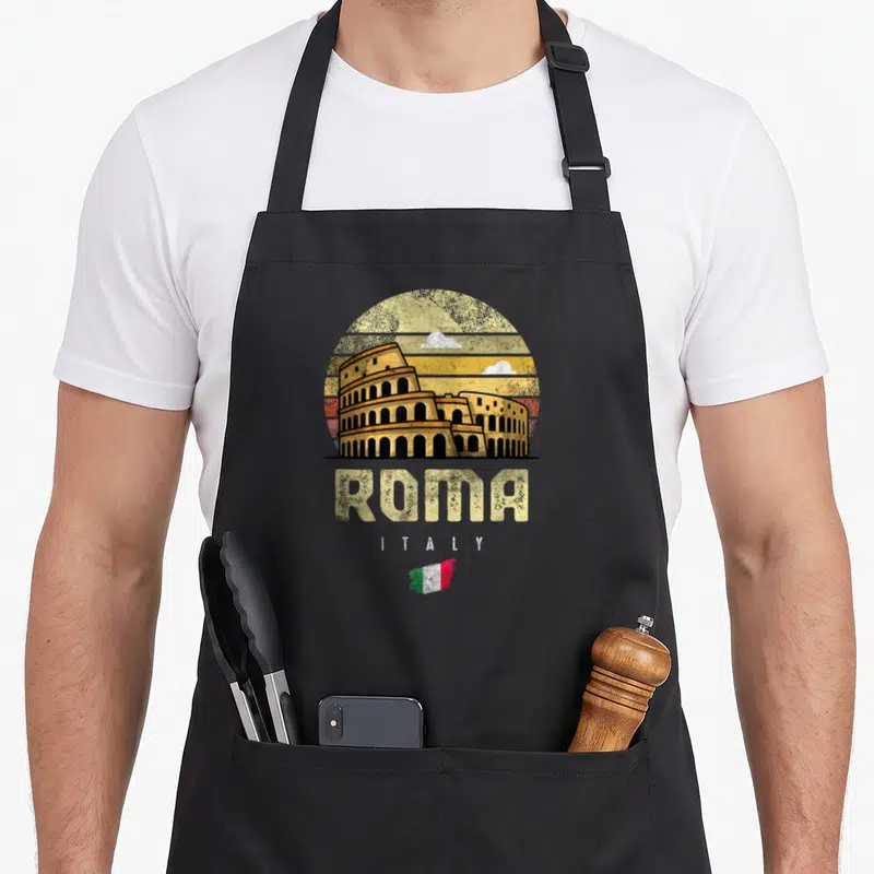 Tablier de cuisine noir avec illustration vintage du Colisée, texte ROMA ITALY et petit drapeau italien en bas du motif.