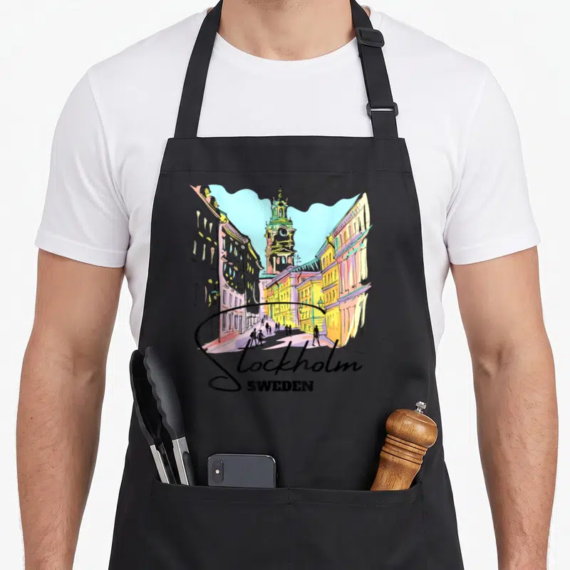 Tablier de cuisine noir avec illustration colorée d'une rue de Stockholm et l'inscription Stockholm Sweden en bas du motif.