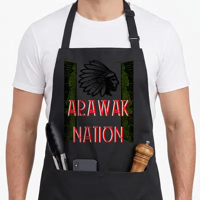 Tablier de cuisine noir avec illustration profil autochtone et texte ARAWAK NATION en lettres rouges et blanches encadré de motifs géométriques verts.