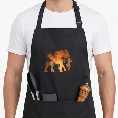 Tablier de cuisine noir avec silhouette d'éléphant orange effet poussière artisticque au centre.