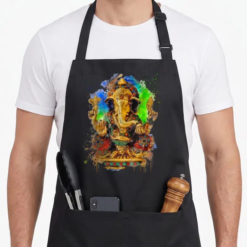 Tablier de cuisine noir avec une illustration colorée du Seigneur Ganesha aux éclats de peinture bleue et verte.