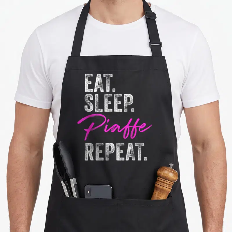 Tablier de cuisine noir avec le texte Eat Sleep Piaffe Repeat en blanc et rose vif.