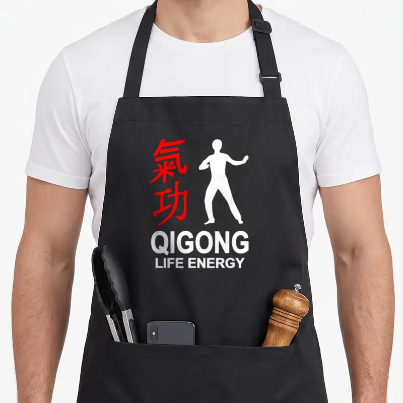 Tablier de cuisine noir avec silhouette blanche, caractères rouges et texte Qigong Life Energy imprimé au centre.