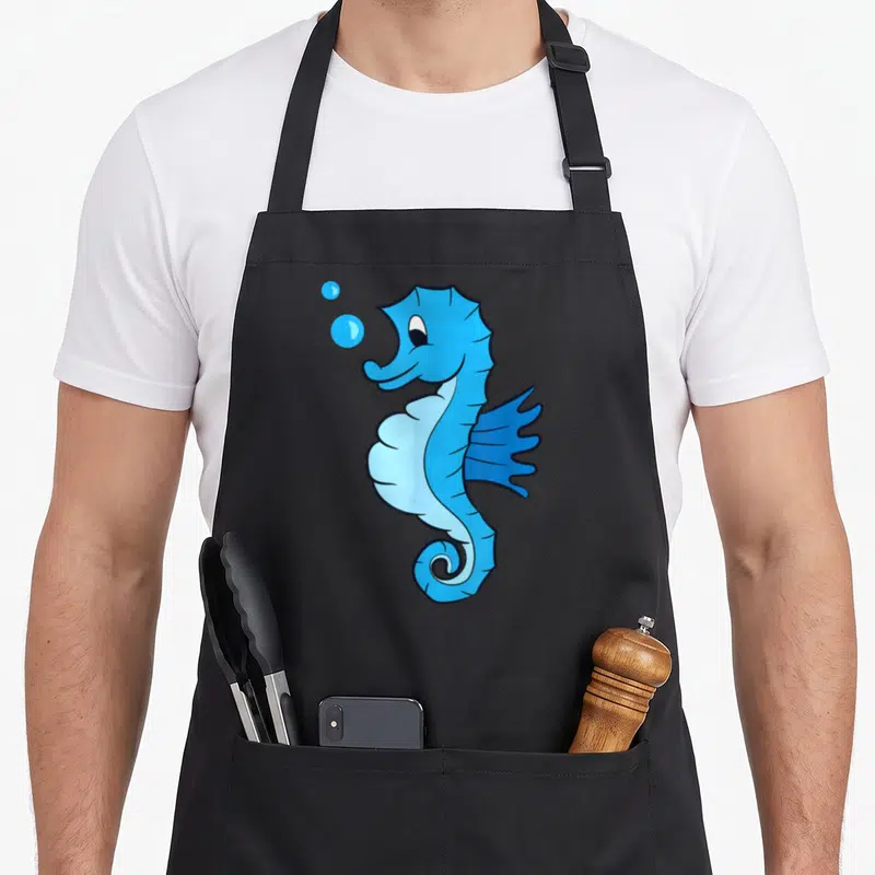 Tablier de cuisine noir avec un hippocampe bleu cartoon et deux bulles d'eau flottant au-dessus.