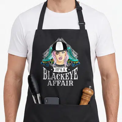 Tablier de cuisine noir avec une patineuse aux cheveux roses, un casque et des patins turquoise encadrés par un motif géométrique blanc.