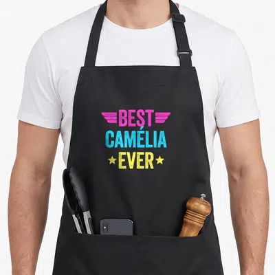 Tablier de cuisine noir avec inscription Best Camélia Ever en lettres colorées et ailes stylisées roses.