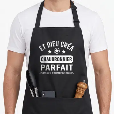 Tablier de cuisine noir avec le texte blanc Et Dieu créa chaudronnier parfait et trois étoiles stylisées au centre.