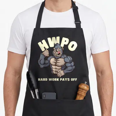 Tablier de cuisine noir avec illustration d'un gorille musclé et le texte HWPO Hard Work Pays Off en beige.