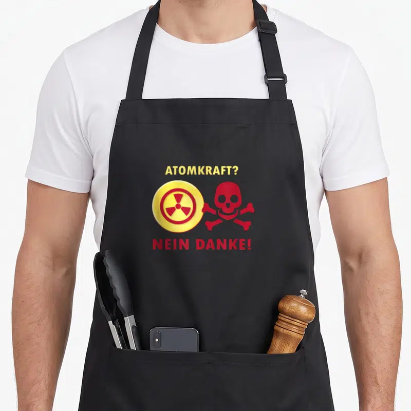 Tablier de cuisine noir avec le texte Atomkraft Nein Danke et un crâne rouge à côté d'un symbole de radiation jaune.