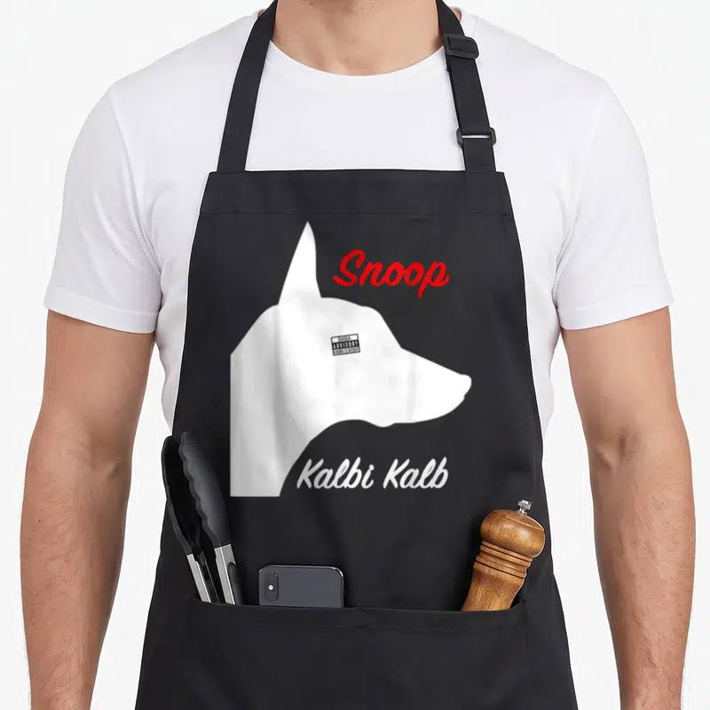 Tablier de cuisine noir avec profil de chien blanc, texte Snoop Kalbi Kalb et étiquette avertissement parents.