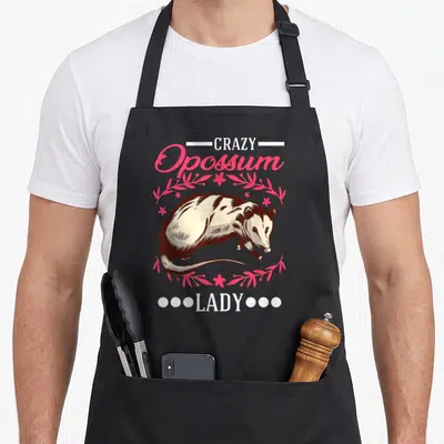 Tablier de cuisine noir avec illustration d'opossum et texte Crazy Opossum Lady en rose et blanc.