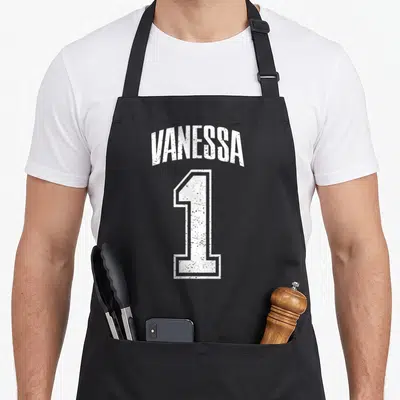 Tablier de cuisine noir avec l inscription Vanessa 1 en typographie blanche style maillot de sport délavé