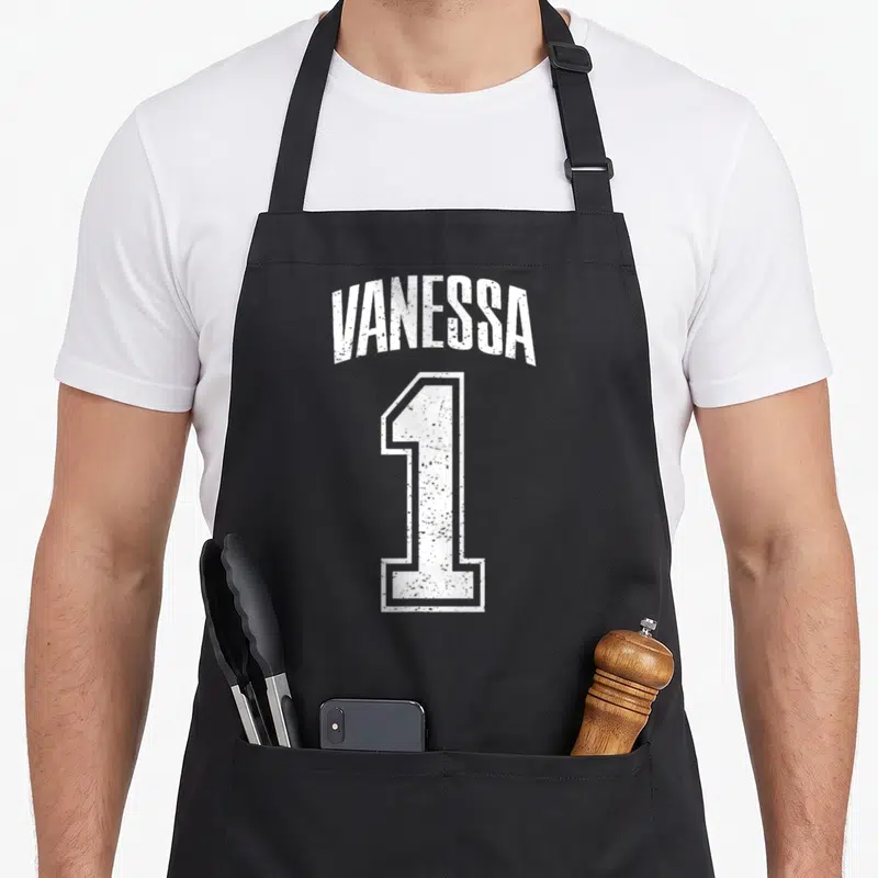 Tablier de cuisine noir avec l inscription Vanessa 1 en typographie blanche style maillot de sport délavé