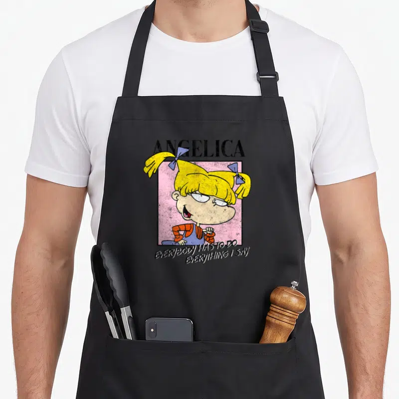 Tablier de cuisine noir avec le personnage Angelica et la phrase Everybody Has To Do Everything I Say imprimés en couleur.