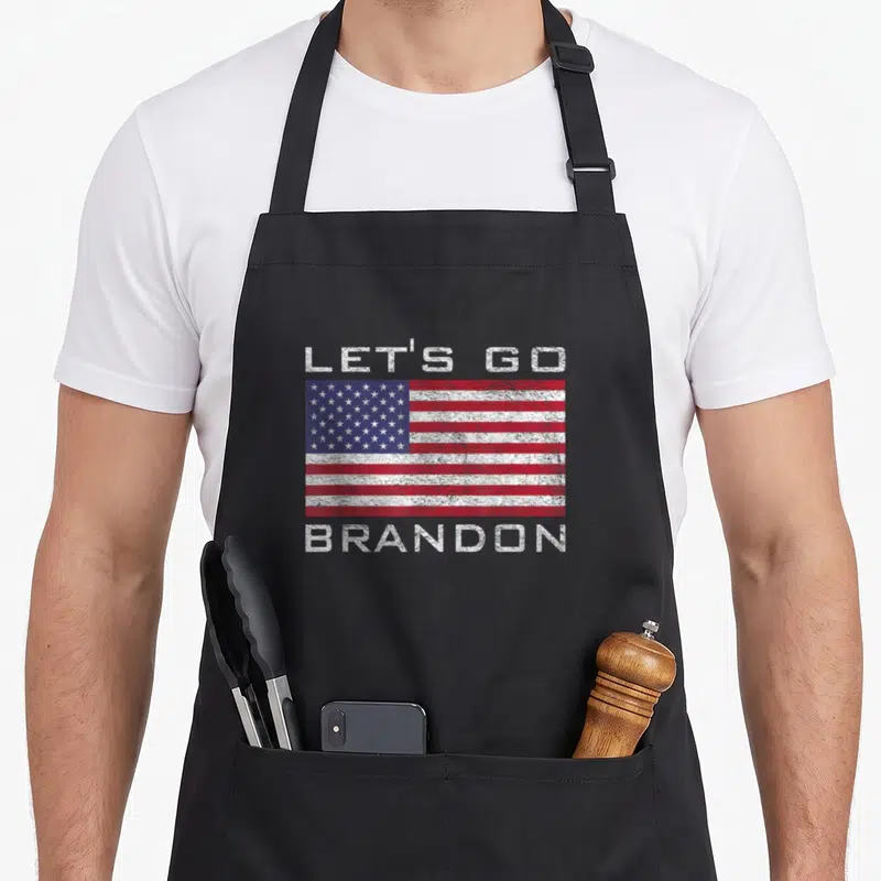 Tablier de cuisine noir avec le drapeau américain et le texte Let's Go Brandon imprimé en blanc sur le devant.
