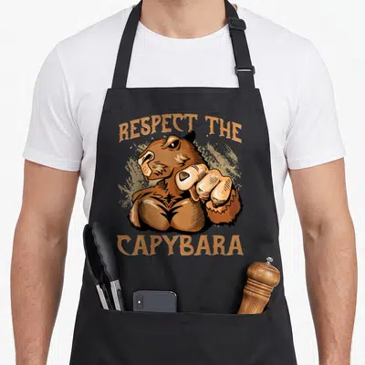 Tablier de cuisine noir avec illustration d'un capybara musclé pointant et texte respect the capybara pour rongeurs.