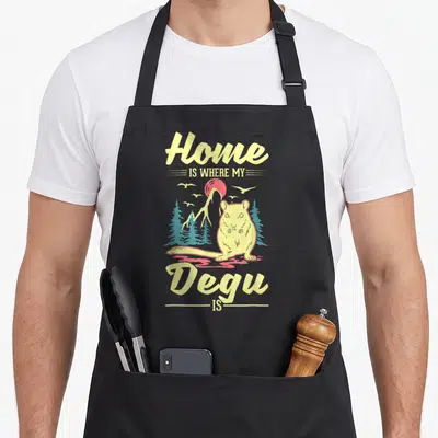 Tablier de cuisine noir avec illustration d'un dégu jaune devant des montagnes et le texte Home is where my degu is degu.