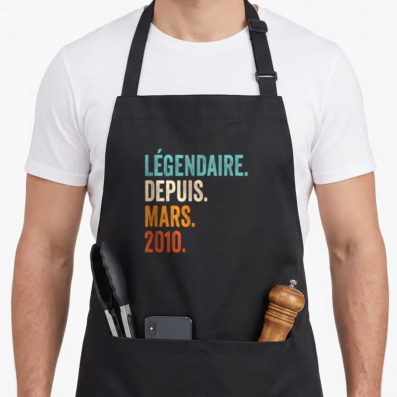 Tablier de cuisine noir avec le texte légendaire depuis mars 2010 imprimé en lettres colorées et stylisées.