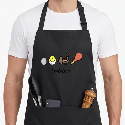 Tablier de cuisine noir avec illustration d'un œuf, poussin, dinde et jamon d'avatar sous le mot Evolution.