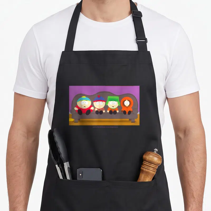 Tablier de cuisine noir avec quatre personnages animés assis côte à côte sur un canapé gris devant un mur violet.